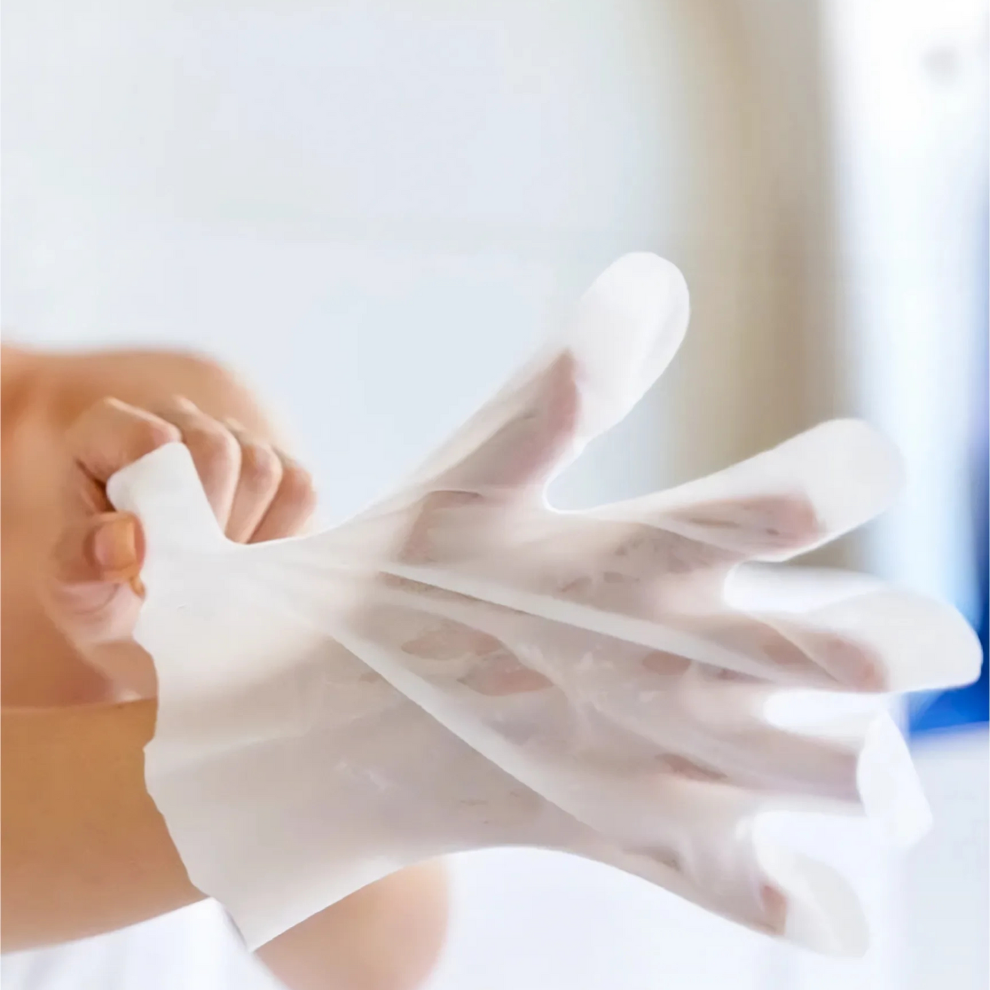 Person wearing a transparent vinyl glove against a blurred background