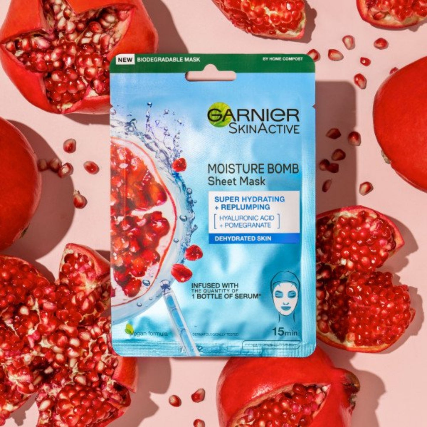Garnier SkinActive moisture bomb sheet mask surrounded by pomegranate fruits on a pink background