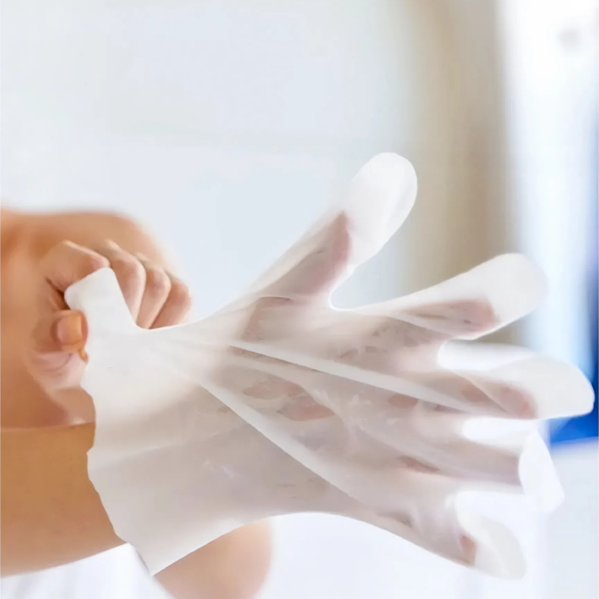 Person wearing a transparent vinyl glove against a blurred background